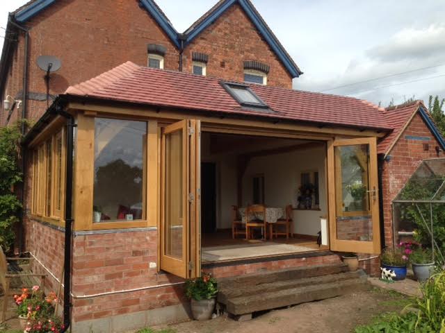An oak framed conservatory with a set of oak bi folding doors opening up the room to the...