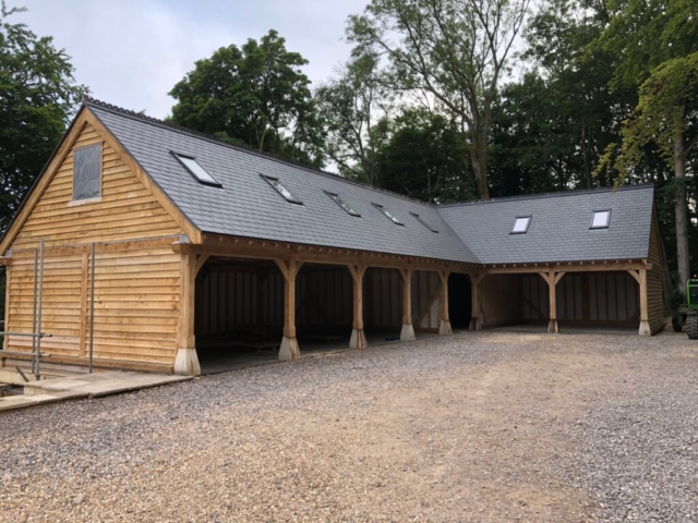 A seven bay, 'L' shaped oak framed garage with rooms upstairs and oak cladding.