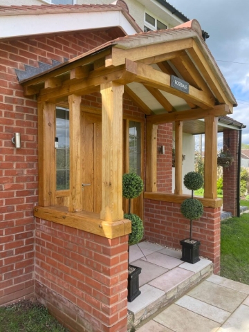 An open oak framed porch sat on red brick wall and a red tiled roof