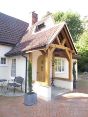 Oak Framed porch with curved braces on a rendered white wall