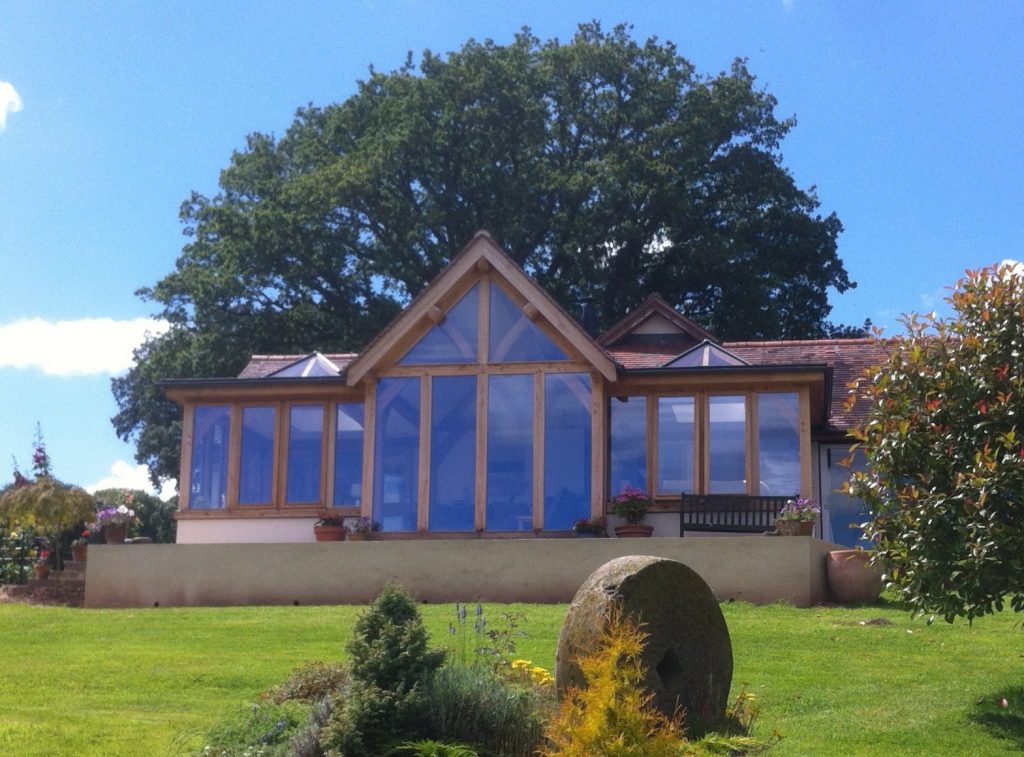 Large glazed oak framed extension with gable and lantern sections.