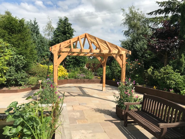 Oak gazzebo with curved braces all round and a hipped roof.