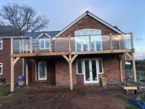 Oak framed balcony with steel hand rails and glass balustrade.