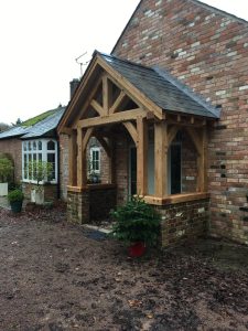 Large oak framed porch sat on a brick wall with a natural slate roof.