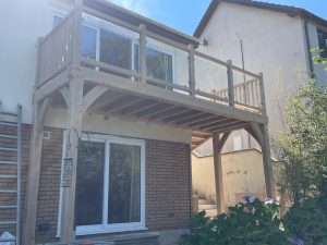 Oak framed balcony with glass to the front and spindles to the sides.